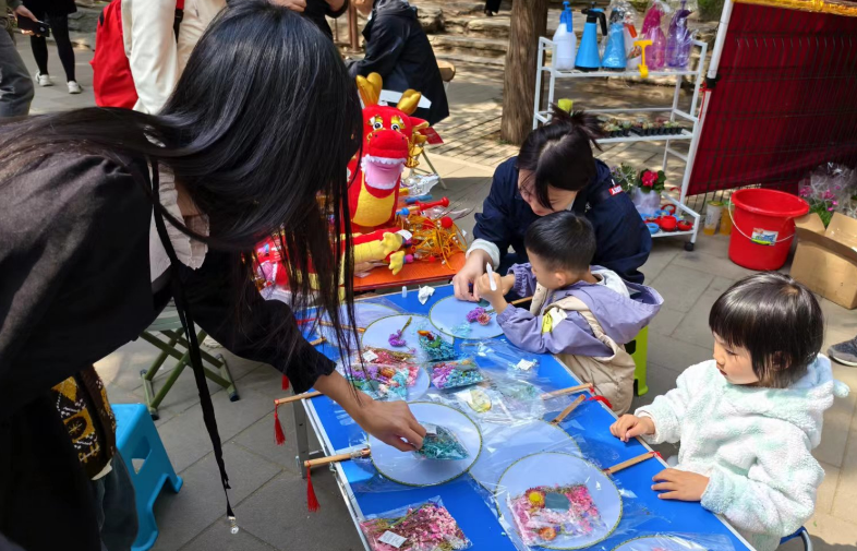 北京陶然亭公园开设的陶然市集上，小游客们正在体验画扇面。人民网记者 乔业琼摄